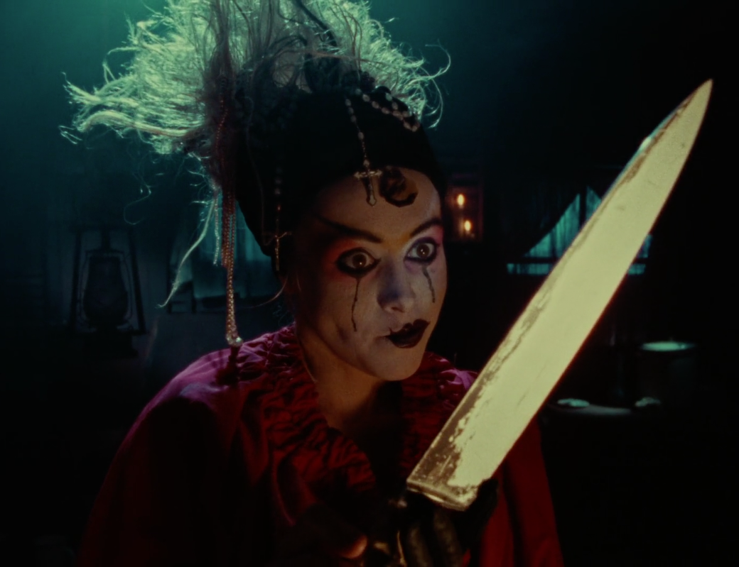 Rhys Davis as Betty Holding a Large Knife
